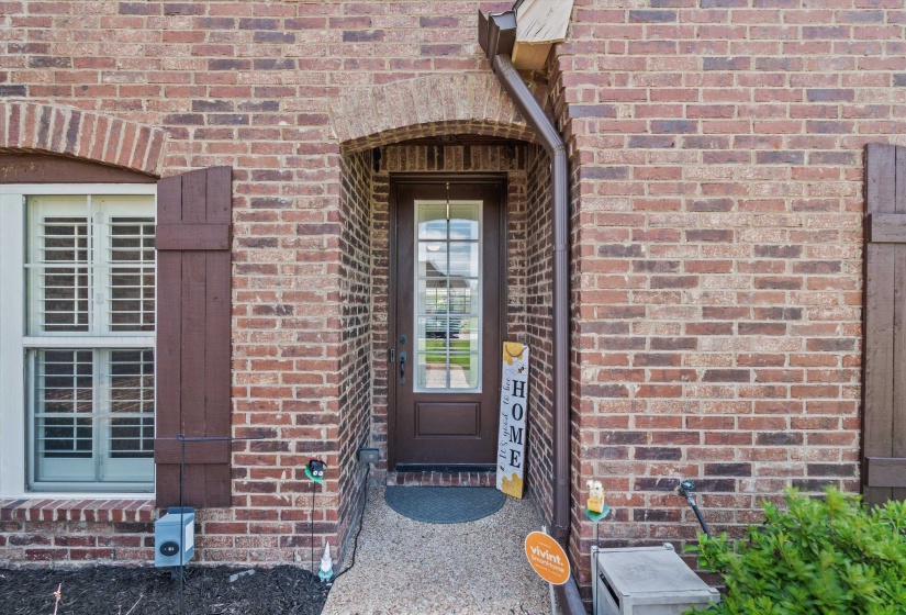 Brick exterior featuring an arched entryway and a transom window above the front door