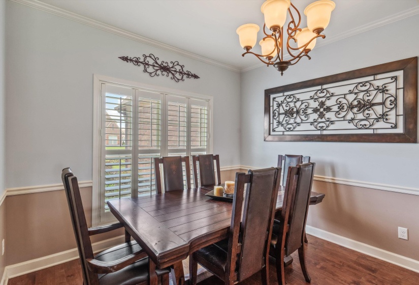 Dining space featuring wood-finish flooring, white crown molding, and wainscoting