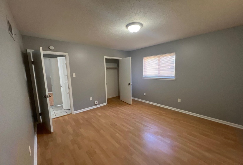 Spacious room featuring wood-finish flooring, a ceiling-mounted light fixture, and a window with blinds