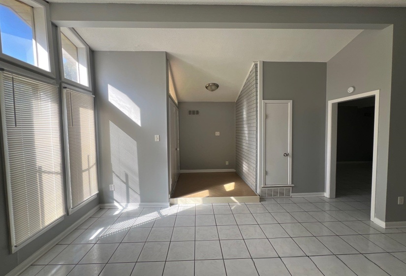 Expansive tiled flooring anchors this interior space, featuring a prominent wall of vertical windows equipped with blinds
