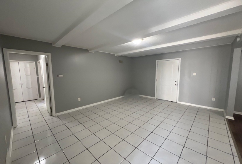 Open concept room with neutral grey wall paint and white trim, featuring white square tile flooring