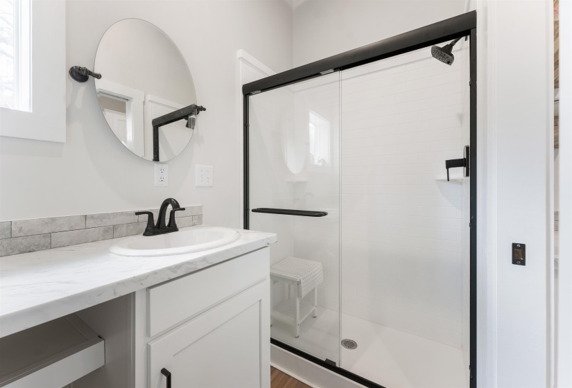 Modern bathroom featuring a walk-in shower with clear glass enclosure and matte black hardware