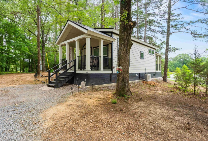 Charming cottage-style home featuring a covered front porch with white columns, dark railings, and exterior steps