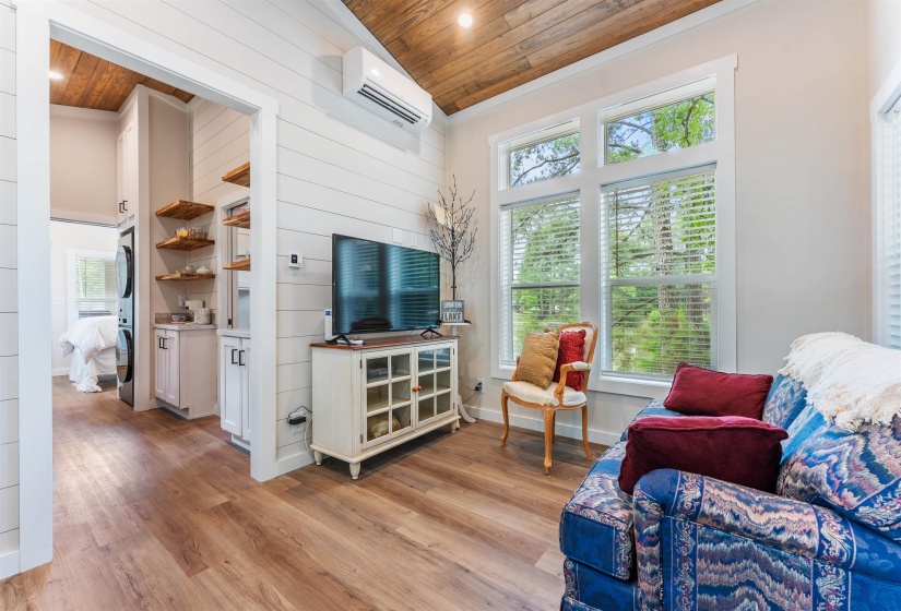 Living area featuring wood-finish flooring, shiplap accent wall, and a sloped wood-paneled ceiling