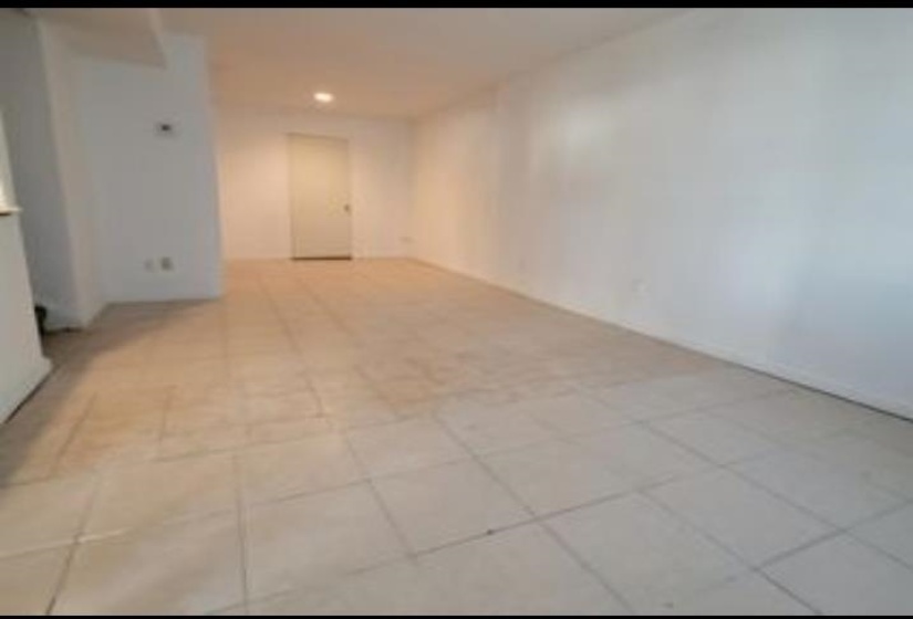 Spacious interior room featuring light-toned tile flooring, recessed lighting, and crisp white walls