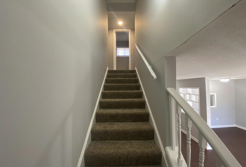 Carpeted staircase with white railings, light gray walls, and recessed lighting