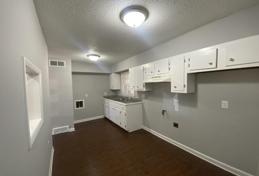 Kitchen featuring white cabinetry, a double basin sink, dark wood-finish flooring, and light gray walls