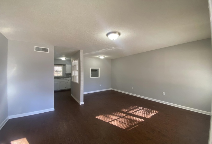 Spacious room with dark wood-finish flooring and light gray walls