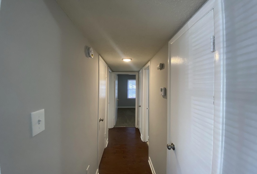 Hallway featuring light gray walls, dark wood-finish flooring, and white trim