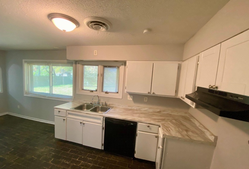 Kitchen featuring white cabinetry, a double basin stainless steel sink, black dishwasher, and black range hood