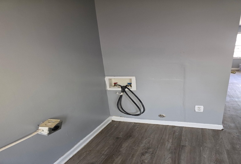 Utility area featuring wood-finish flooring, a washer hookup, and a dryer vent