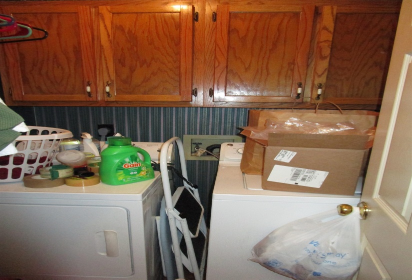 Laundry area featuring wood-finish cabinetry, striped wall covering, and a white appliance pairing