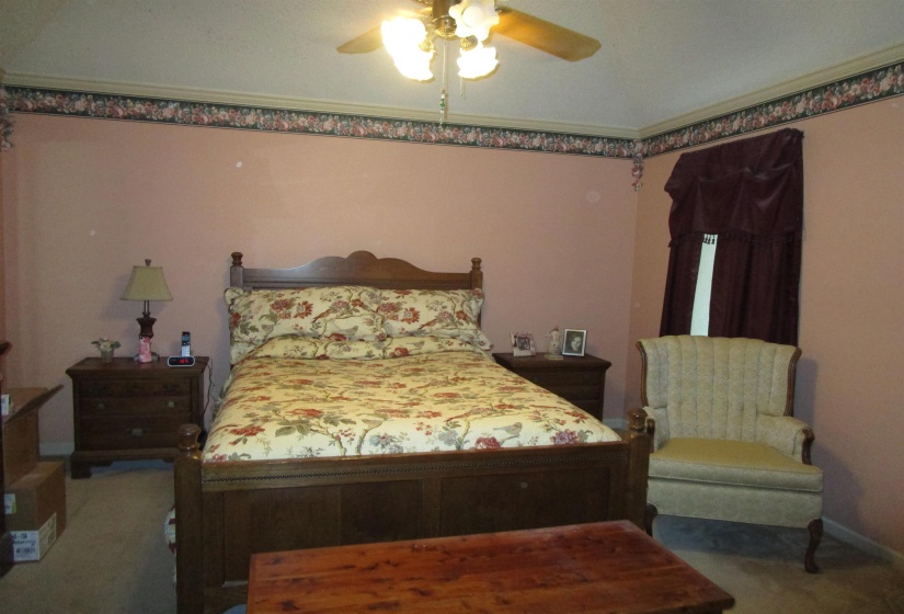 Bedroom featuring a ceiling fan with integrated lighting, a crown molding accent, and a floral wallpaper border