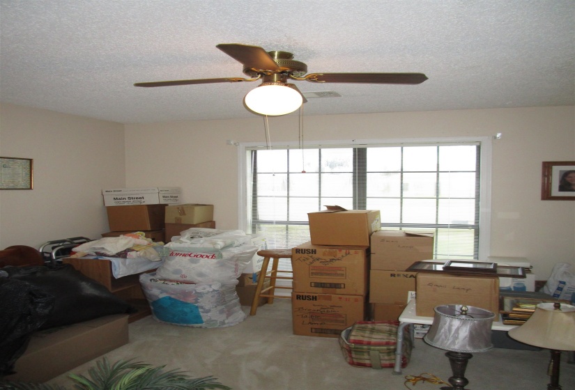 Recessed lighting, textured ceiling, large window with blinds, light-toned wall paint, and neutral carpeting