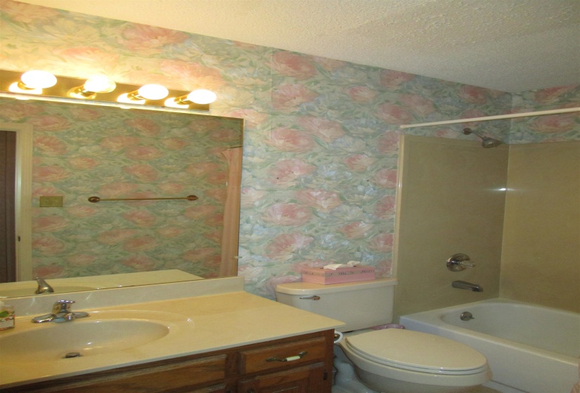 Bathroom featuring a single vanity with an integrated sink, a built-in mirror, and a wall-mounted light fixture  Located between bedroom 2 & 3