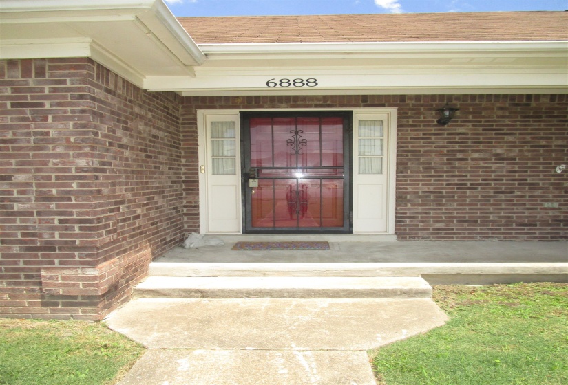 Brick exterior with white trim, a red entry door, and a black security screen door