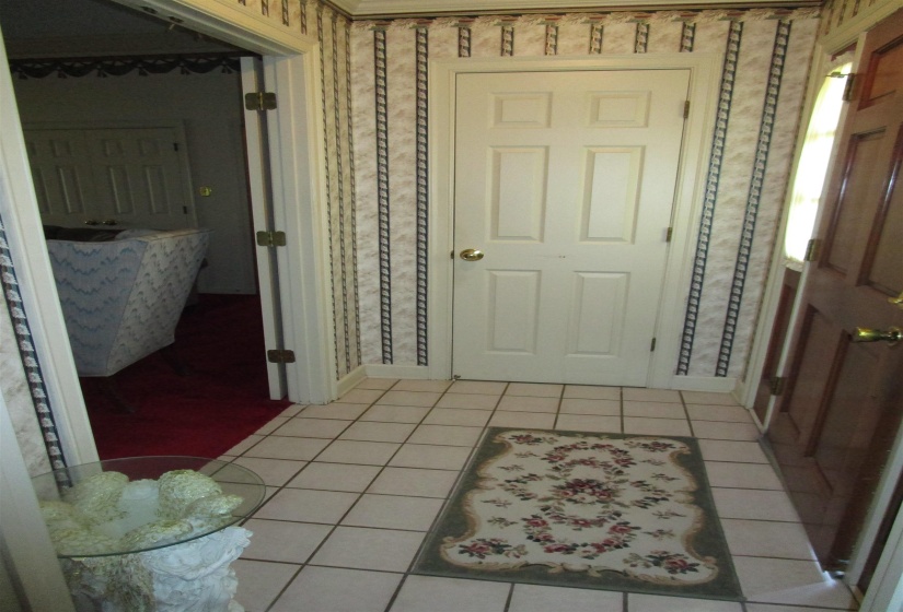 Tiled flooring entry space featuring patterned wallpaper, white baseboards, and a paneled interior door