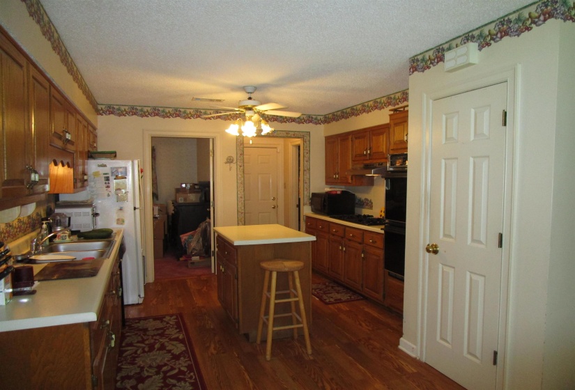 Kitchen featuring wood-finish flooring, a central island with countertop, and extensive wood cabinetry