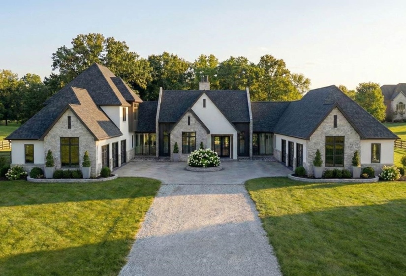 Expansive estate featuring a light stone and stucco exterior, multiple gabled roofs, and a circular driveway