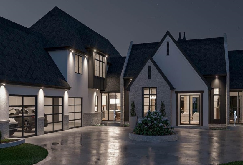 Contemporary exterior featuring a stone and stucco facade, a dark shingle roof, a circular driveway with a central planted bed, three glass panel garage doors, and exterior lighting fixtures