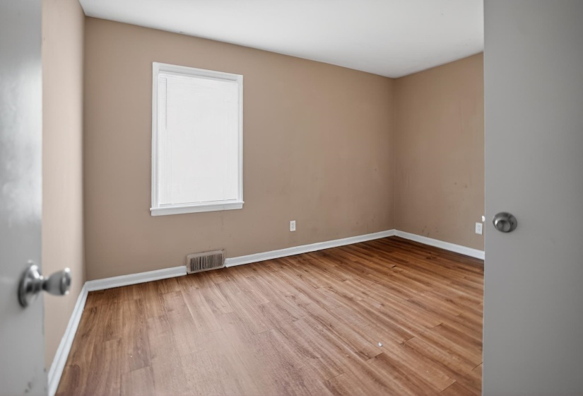 Room featuring wood-finish flooring, neutral wall paint, white baseboards, and a window with white trim