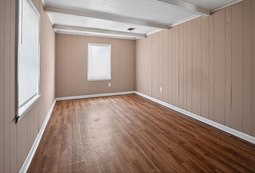 Room featuring wood-finish flooring, vertical paneling, and exposed ceiling beams