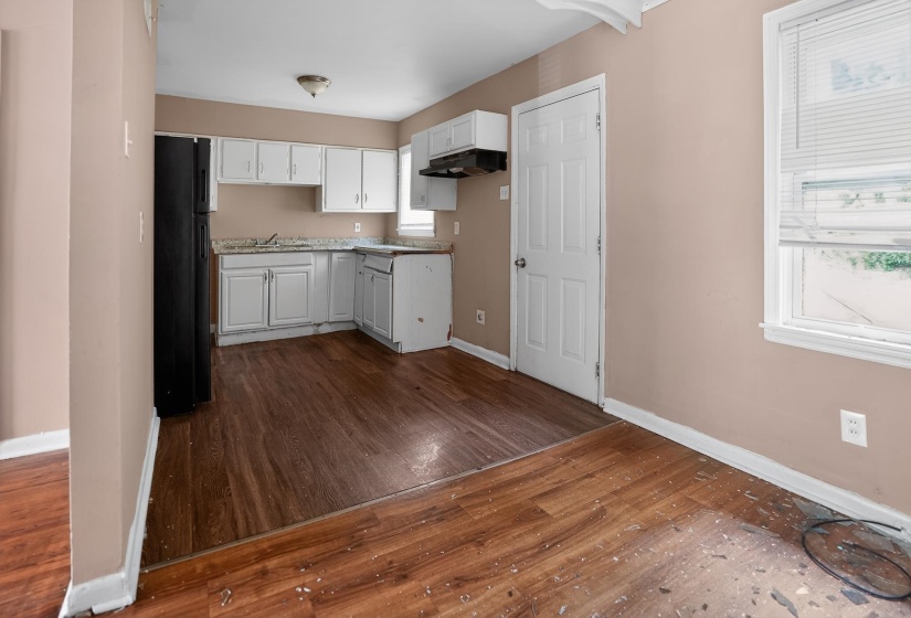 Kitchen area with wood-finish flooring, white cabinetry, and light-toned countertops