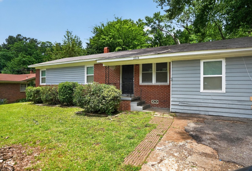 Brick and siding exterior with a front entry porch and mature shrubbery