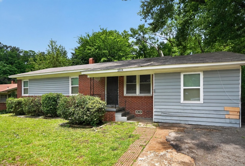Brick and siding exterior featuring a covered front porch and mature landscaping