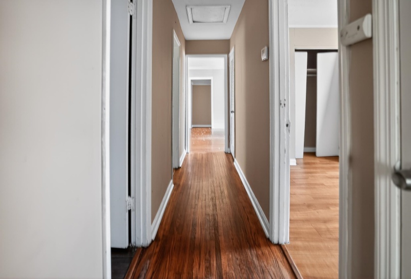 Hallway featuring wood-finish flooring, painted walls, and white trim