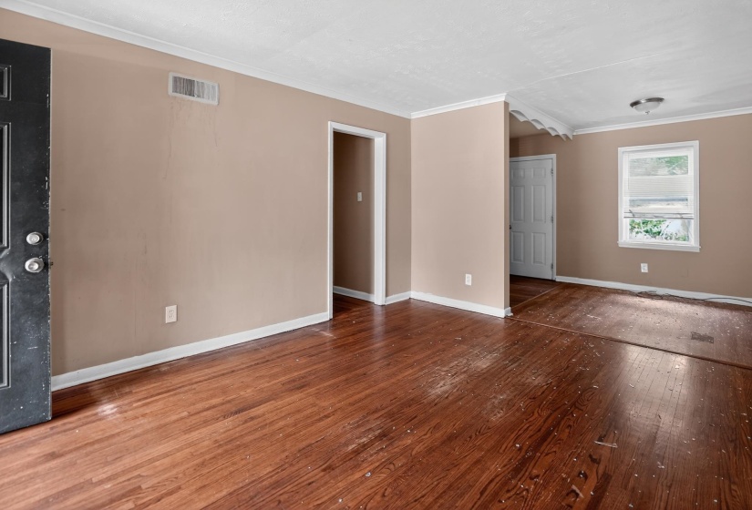 Open concept living space featuring wood-finish flooring, neutral wall tones, white trim, a double-paned window, and a ceiling-mounted light fixture
