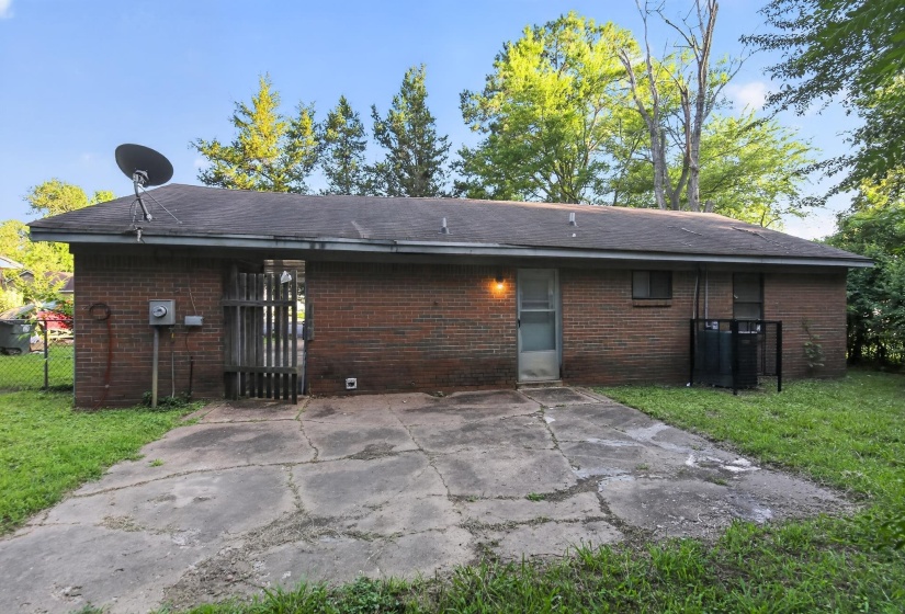 Brick exterior featuring a concrete patio, exterior lighting, and a fenced area