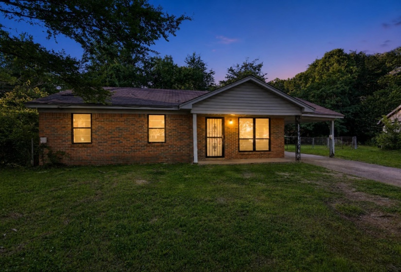 Brick exterior residence featuring a front porch with an overhead light fixture, a carport, and a front entry door with a security screen