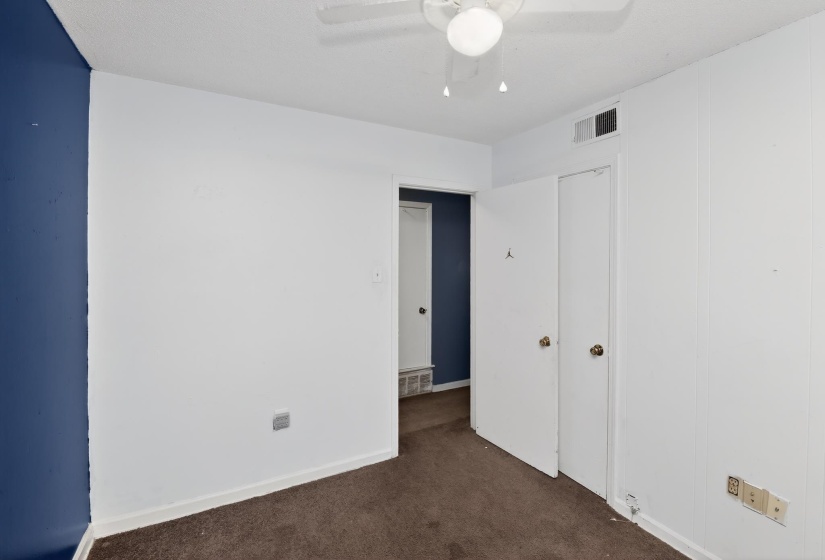 Interior room featuring a ceiling fan with light fixture, white paneled walls, and a blue accent wall