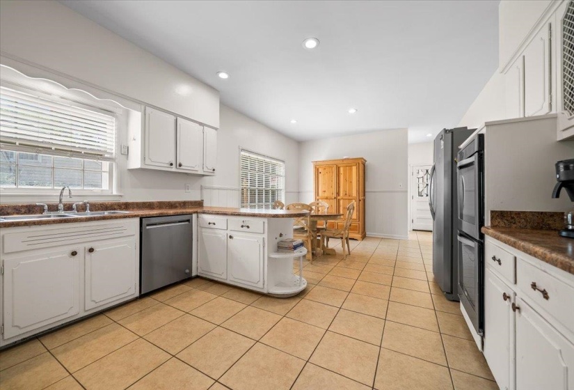 Spacious kitchen featuring tile flooring, white cabinetry, a built-in dishwasher, and recessed lighting