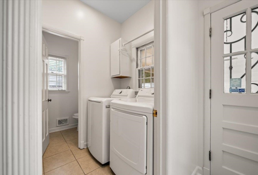 Dedicated laundry area featuring tile flooring, white cabinetry, and a window with blinds