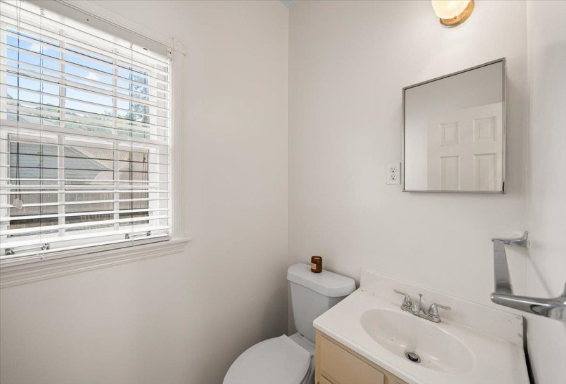 1/2 bathroom featuring a window with blinds, a built-in vanity with a white sink, a wall-mounted medicine cabinet, and a toilet