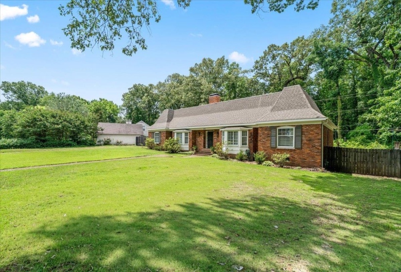 Brick exterior residence featuring a gabled roofline, bay window, and dark shutters