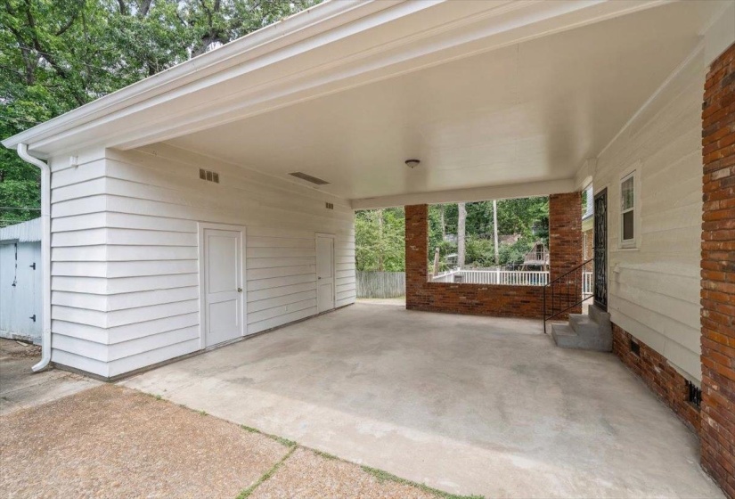Covered carport featuring a concrete floor, white siding, and two storage doors