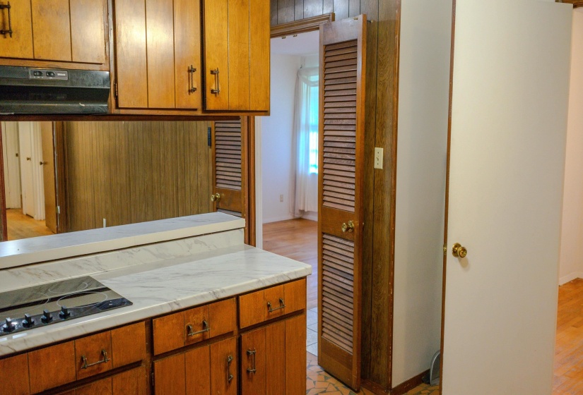 Kitchen area with wood cabinetry, light-toned countertop, and integrated cooktop