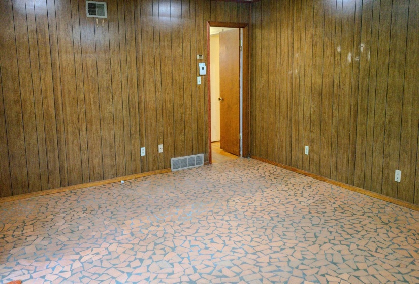 Room featuring wood paneling, a full-lite wood door, mosaic tile flooring, and baseboard trim