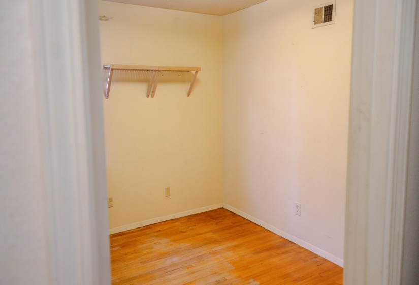 Room with wood-finish flooring, light-toned walls, and a built-in shelving unit