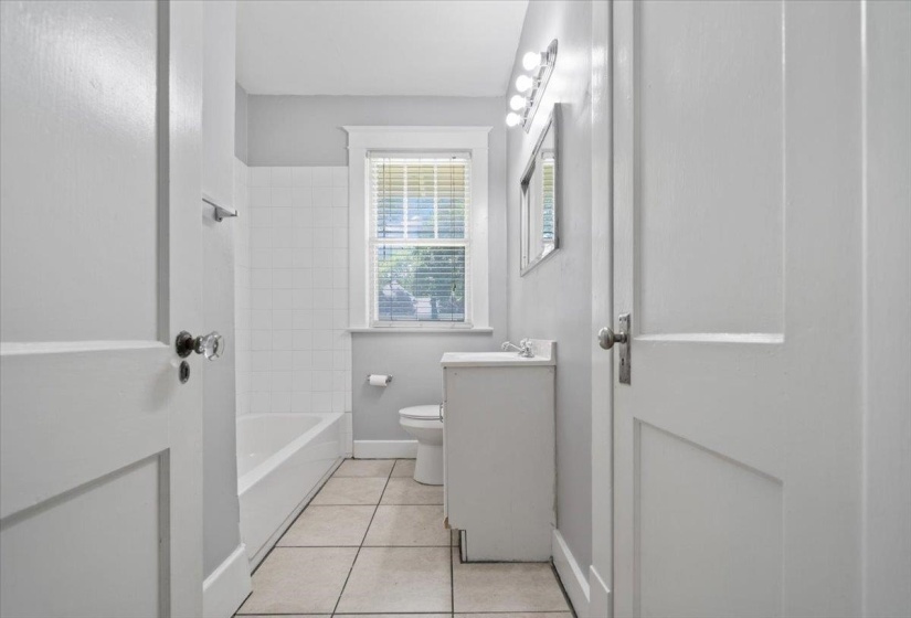 Bathroom featuring white subway tile shower surround, beige tile flooring, and a vanity with an integrated sink