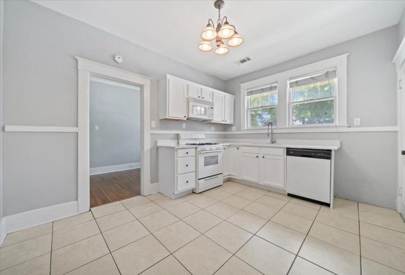 Kitchen featuring tile flooring, white cabinetry, a gas range, a dishwasher, and a mounted microwave