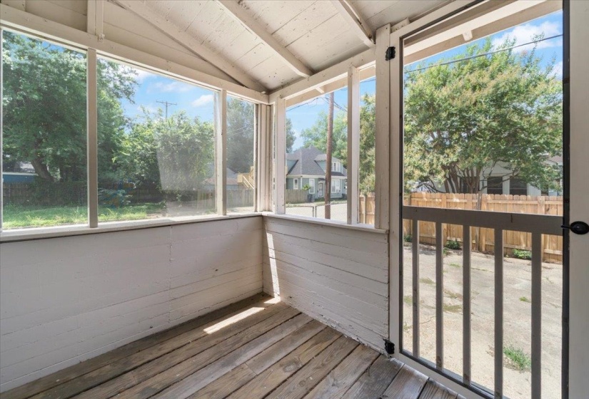 Screened porch with wood-finish flooring, white paneled walls, and a sloped ceiling