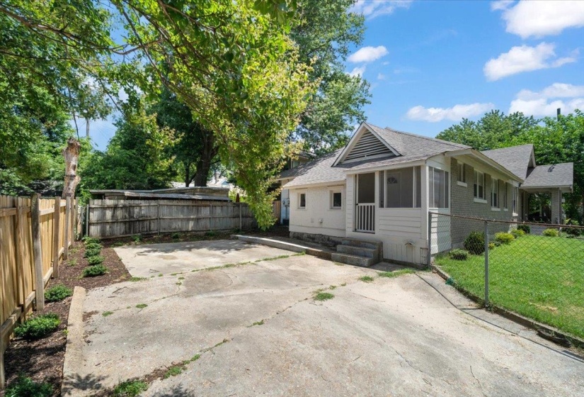 Rear exterior featuring a screened porch entry, concrete patio, and a fully fenced perimeter