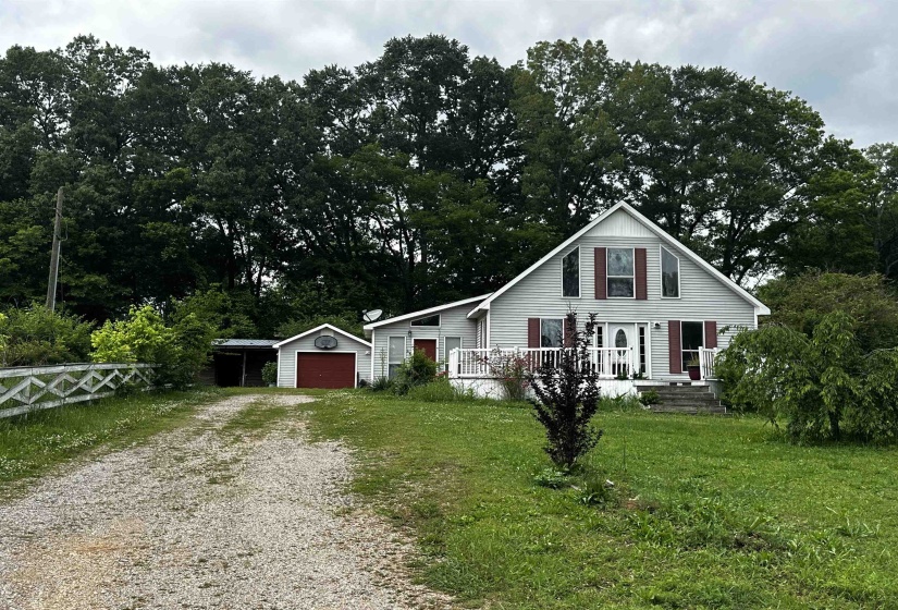 View of front of property featuring driveway, an outbuilding, a carport, and a garage