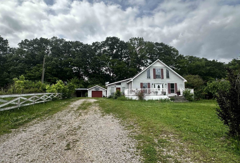 View of front of home with driveway, covered porch, an outdoor structure, and a garage