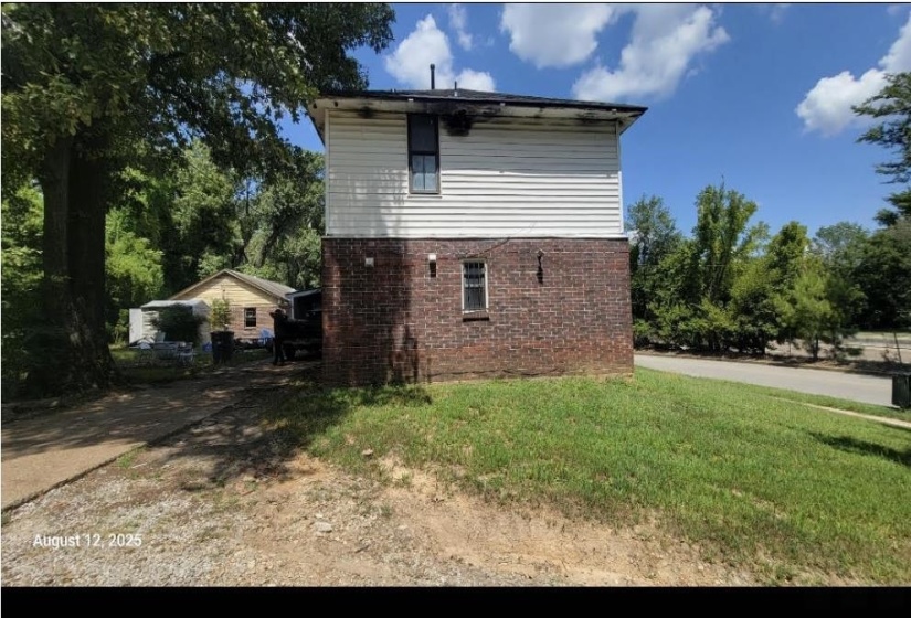 View of property exterior featuring brick siding and a lawn