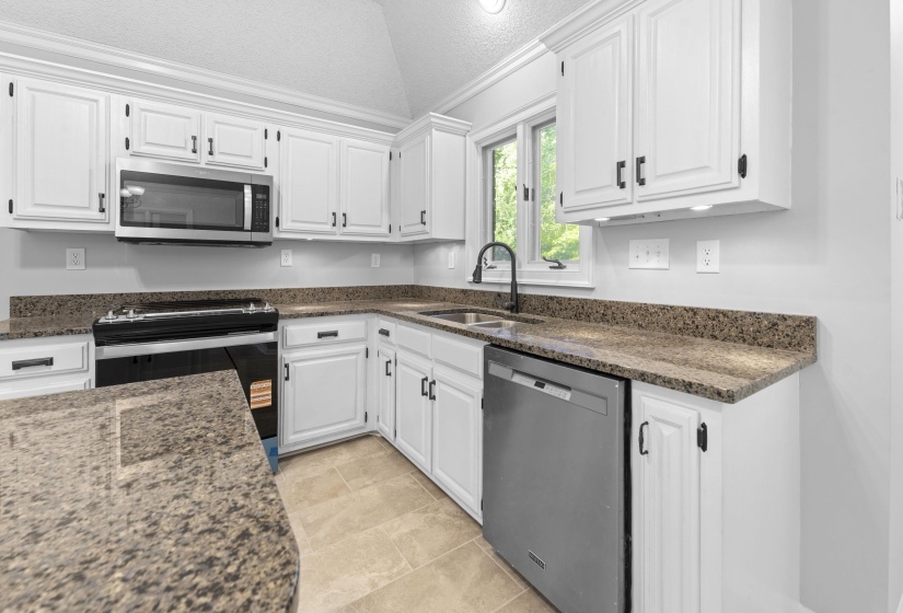 Kitchen featuring white cabinetry, stone countertops, stainless steel appliances, and tile flooring